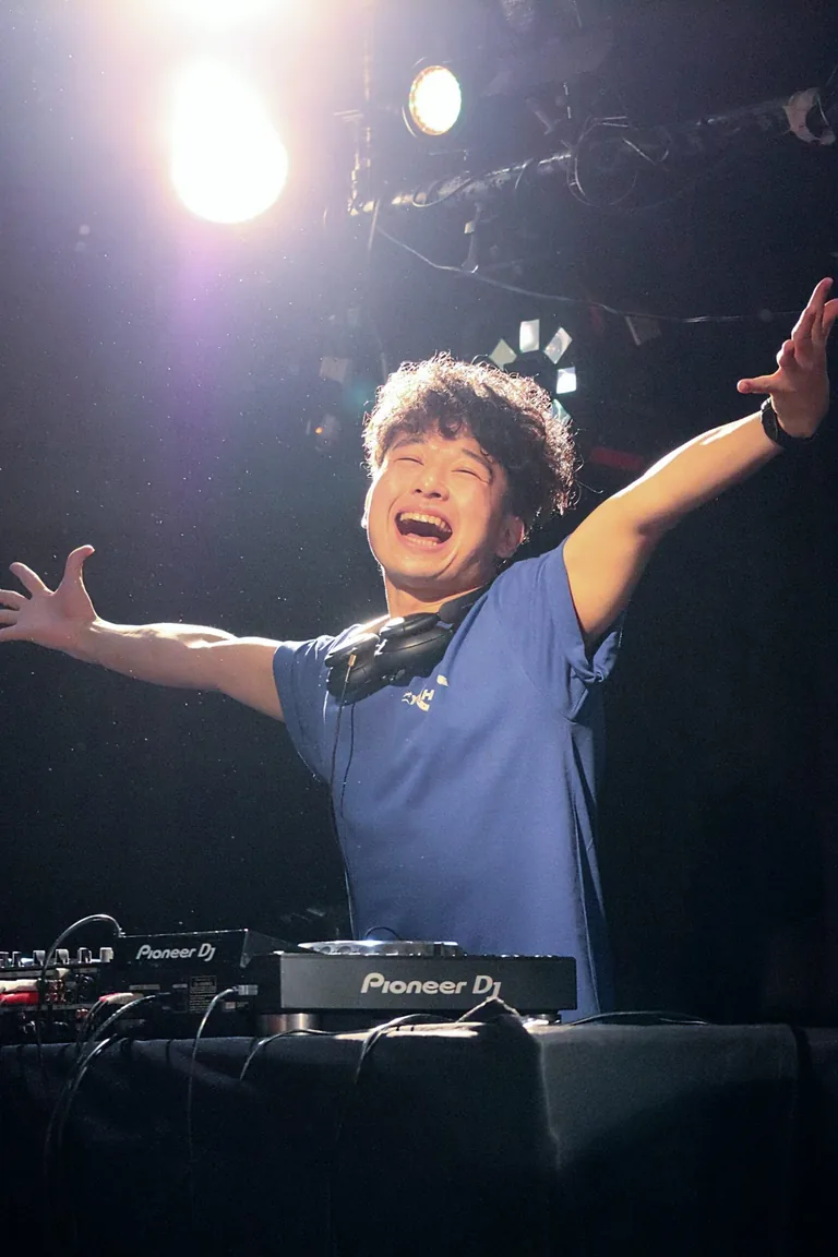 両手を広げて笑顔を見せるDJ YAHAGI
