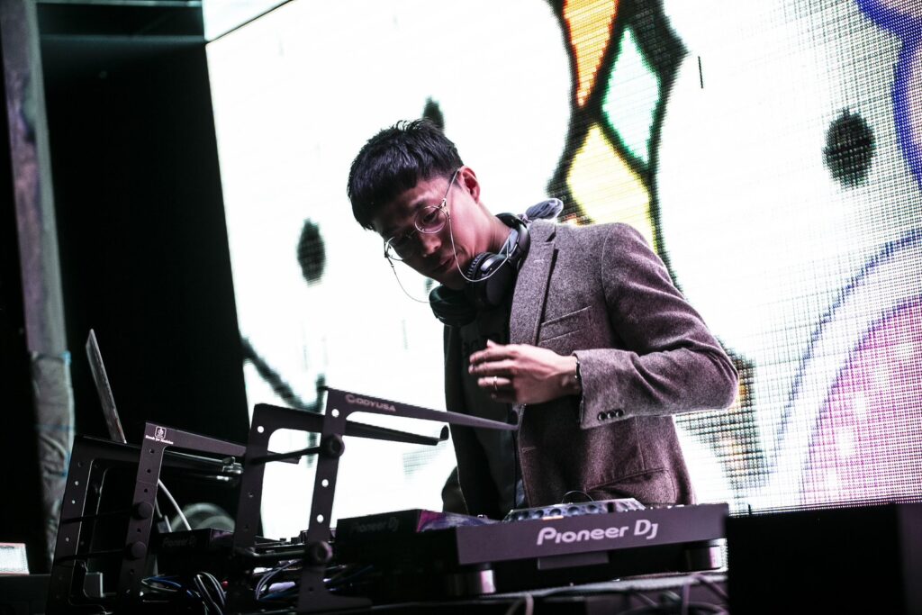 ヘッドホンを首にかけ、DJ機材の前でプレイするお父ちゃん。さん
