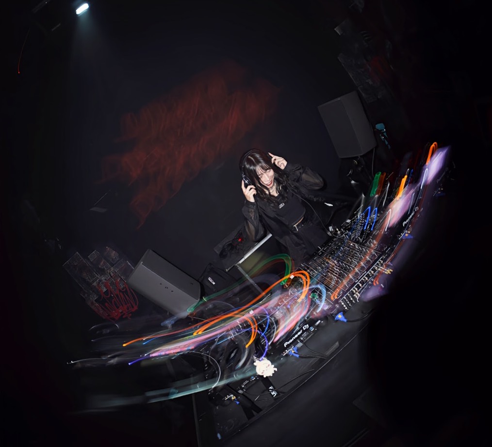 ヘッドホンに手を添え、DJ機材の前でプレイするshikiさん