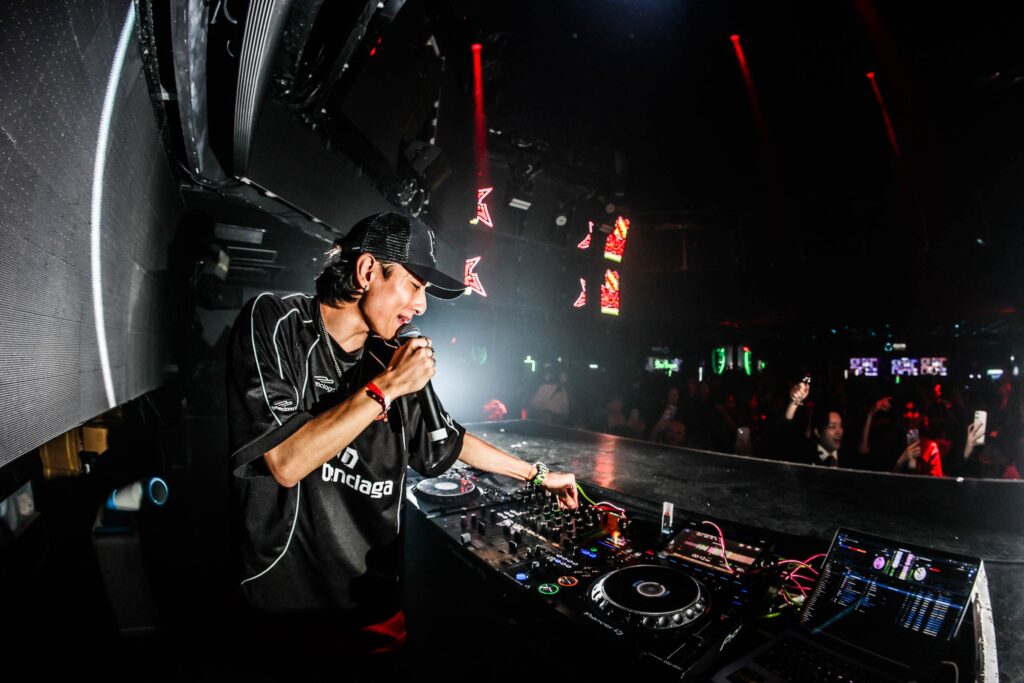 DJブースで機材を操作しながらマイクを持つ村長さん